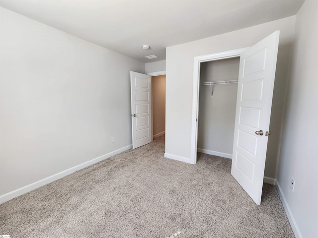 unfurnished bedroom with light carpet and a closet