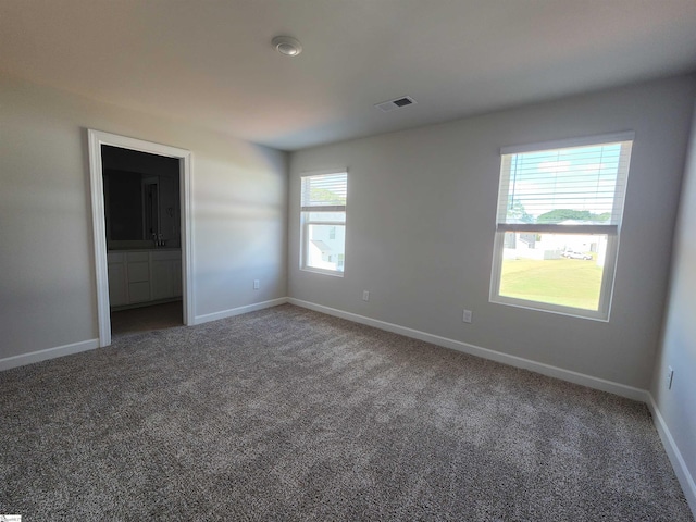 unfurnished room featuring dark carpet and plenty of natural light