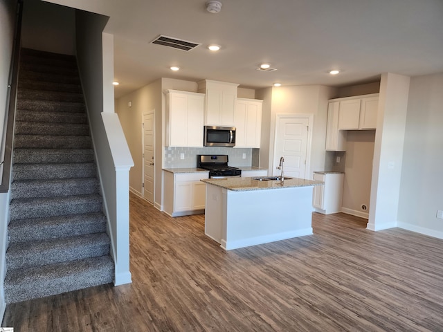 kitchen featuring hardwood / wood-style floors, sink, an island with sink, appliances with stainless steel finishes, and white cabinetry