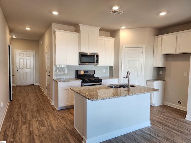 kitchen featuring white cabinets, sink, stainless steel appliances, and an island with sink