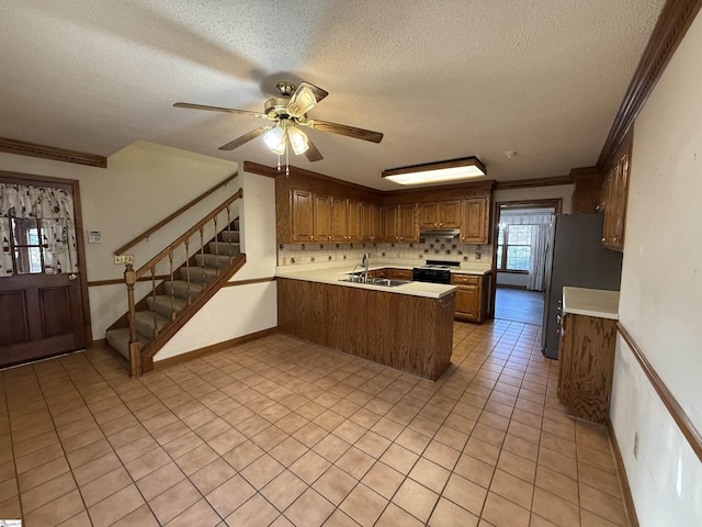 kitchen featuring a peninsula, a sink, light countertops, black range with electric cooktop, and under cabinet range hood