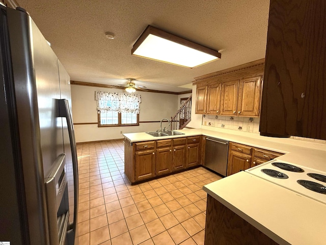 kitchen with light tile patterned floors, a peninsula, ornamental molding, a sink, and appliances with stainless steel finishes