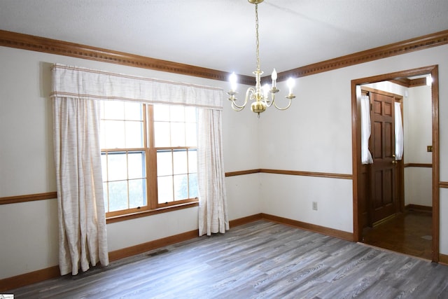 unfurnished room with crown molding, wood finished floors, baseboards, and a chandelier