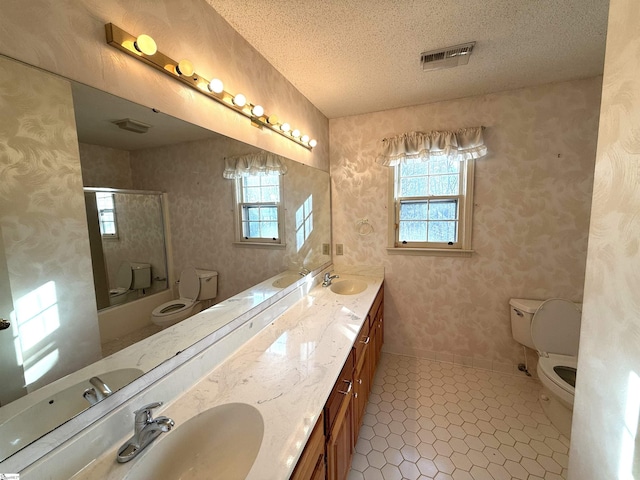 full bath with visible vents, toilet, a sink, a textured ceiling, and wallpapered walls