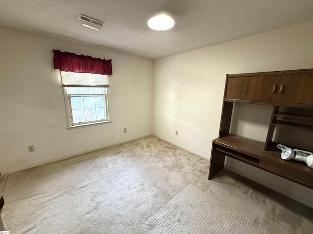 interior space with visible vents, light colored carpet, a textured ceiling, and baseboards