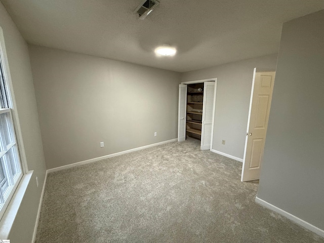 unfurnished bedroom with visible vents, a textured ceiling, a closet, carpet, and baseboards