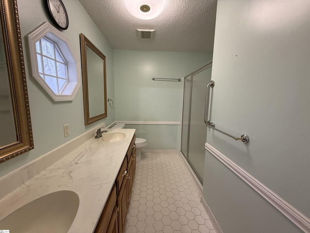 bathroom with a shower stall, toilet, visible vents, and a sink