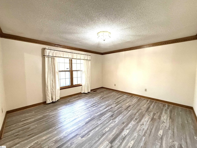 spare room with crown molding, wood finished floors, baseboards, and a textured ceiling