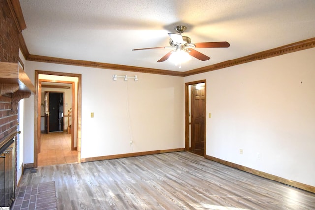 unfurnished living room with light wood finished floors, a fireplace, a textured ceiling, and crown molding