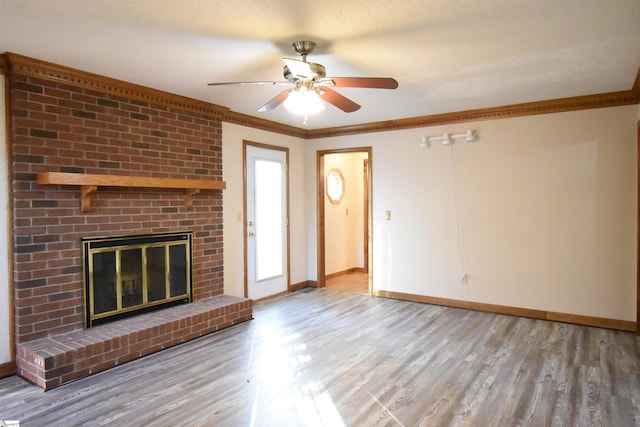 unfurnished living room featuring a fireplace, wood finished floors, baseboards, and ornamental molding