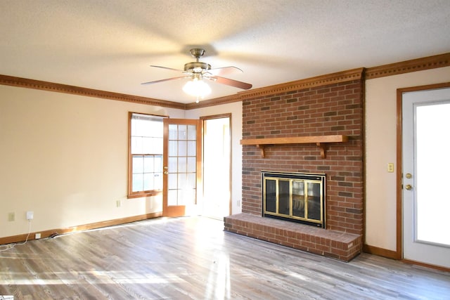 unfurnished living room with a textured ceiling, wood finished floors, a fireplace, crown molding, and baseboards