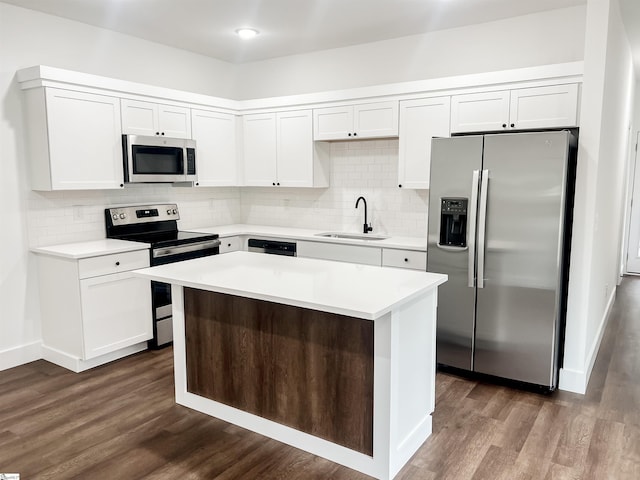 kitchen featuring appliances with stainless steel finishes, dark wood-type flooring, sink, a center island, and white cabinetry