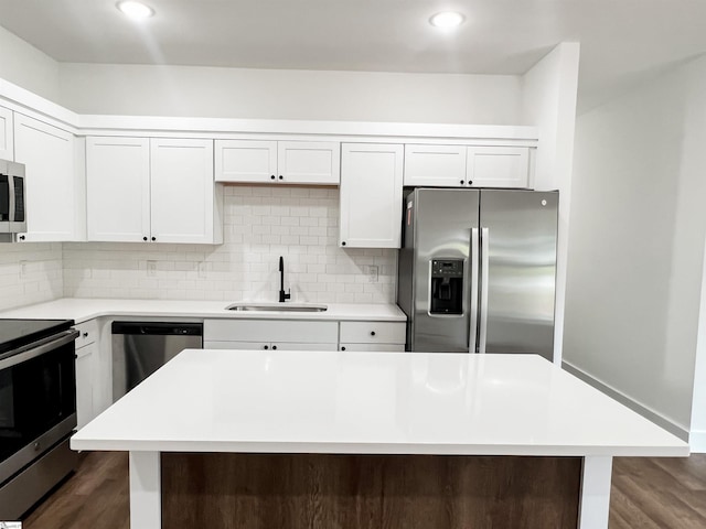 kitchen with stainless steel appliances, dark wood-type flooring, sink, white cabinets, and a center island