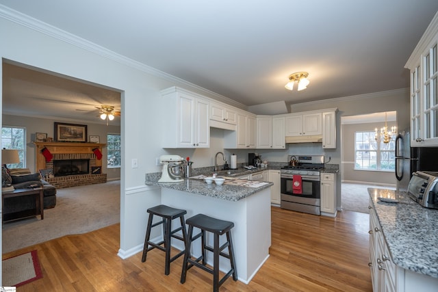 kitchen featuring a kitchen breakfast bar, gas stove, white cabinetry, and sink