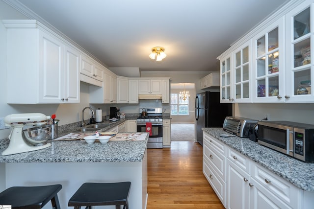 kitchen featuring kitchen peninsula, appliances with stainless steel finishes, light wood-type flooring, sink, and white cabinetry