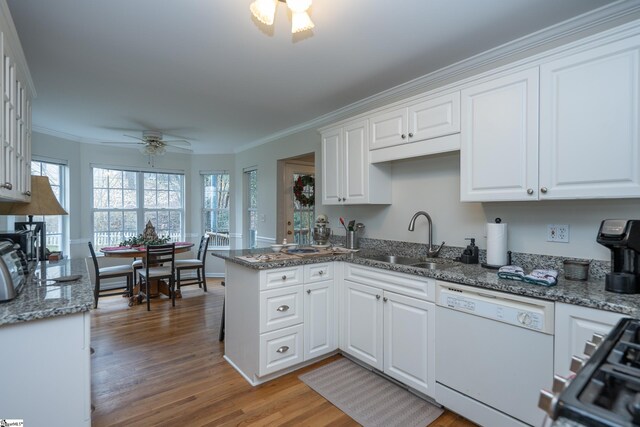 kitchen with white dishwasher, sink, ceiling fan, white cabinetry, and wood-type flooring