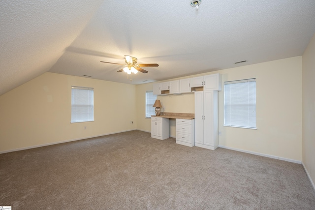 unfurnished bedroom with ceiling fan, lofted ceiling, light carpet, and multiple windows