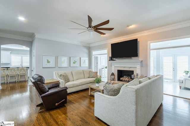 living room featuring crown molding, plenty of natural light, ceiling fan, and dark wood-type flooring