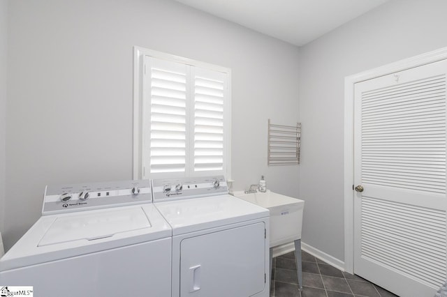 washroom with dark tile patterned flooring, washer and dryer, and sink