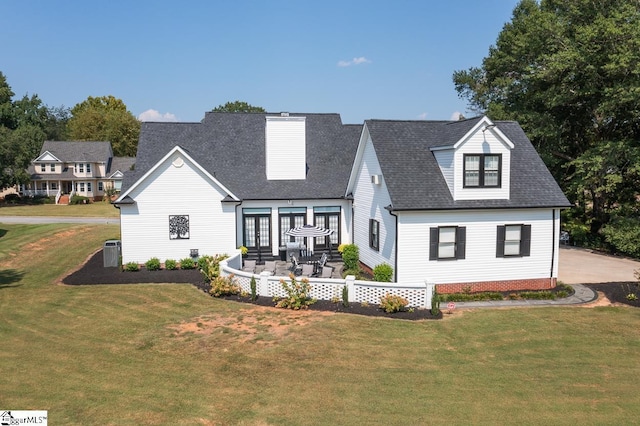 rear view of house with central AC and a lawn