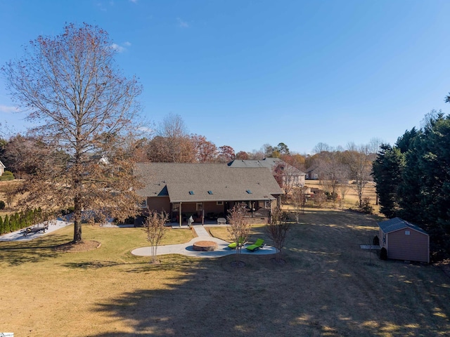 rear view of property featuring a yard and a storage unit