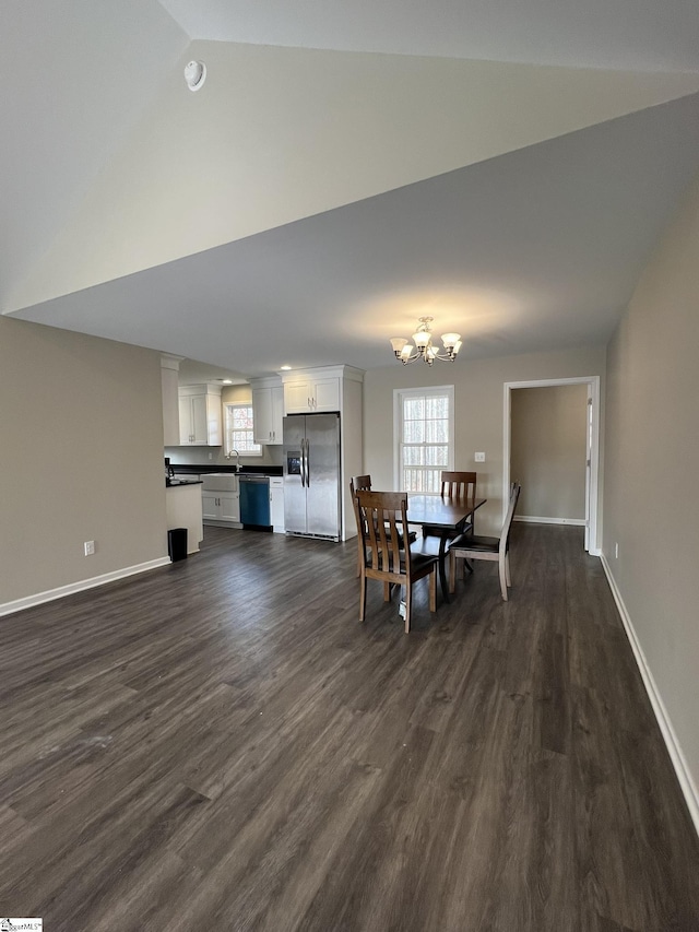 dining room featuring lofted ceiling, an inviting chandelier, dark wood-type flooring, and sink