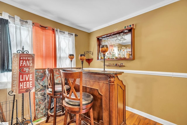 bar with light hardwood / wood-style flooring and ornamental molding