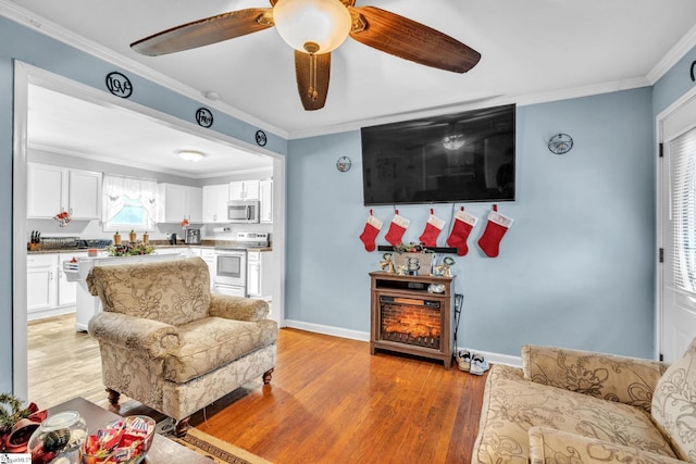 living room with wood-type flooring, ceiling fan, and ornamental molding