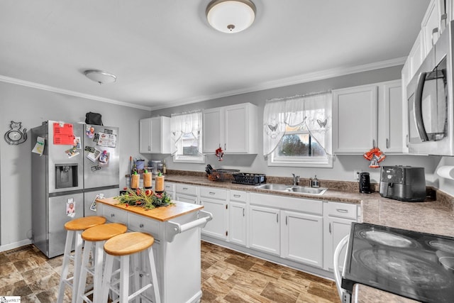 kitchen featuring a kitchen breakfast bar, stainless steel appliances, crown molding, sink, and white cabinetry