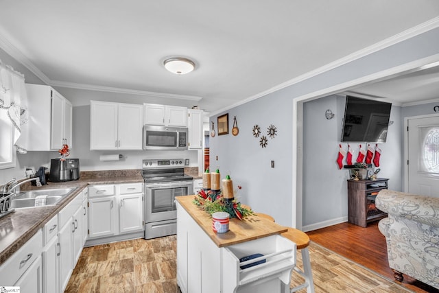 kitchen with sink, light wood-type flooring, ornamental molding, white cabinetry, and stainless steel appliances