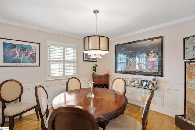 dining space with ornamental molding and light hardwood / wood-style floors