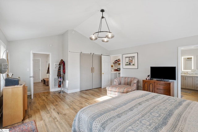 bedroom featuring light hardwood / wood-style floors, ensuite bathroom, a chandelier, and vaulted ceiling