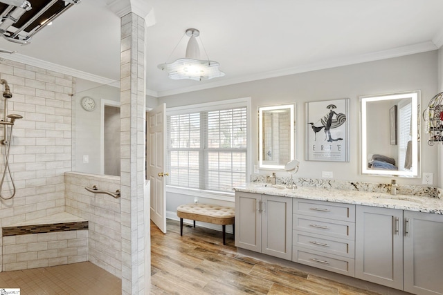 bathroom with vanity, wood-type flooring, ornamental molding, and a tile shower