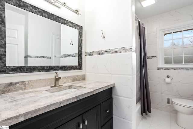 bathroom with walk in shower, vanity, tile walls, and toilet