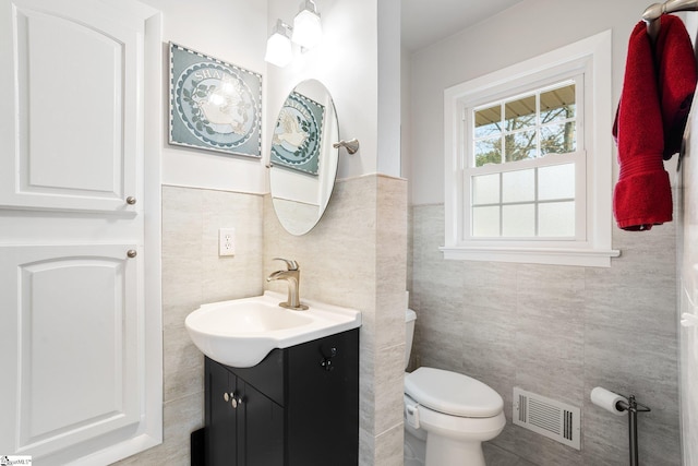 bathroom with tile walls, toilet, and vanity