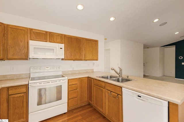 kitchen with kitchen peninsula, wood-type flooring, white appliances, and sink