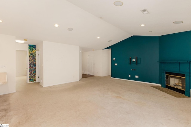 unfurnished living room featuring a tile fireplace, light carpet, and vaulted ceiling