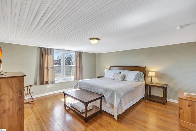 bedroom featuring brick wall and light hardwood / wood-style flooring