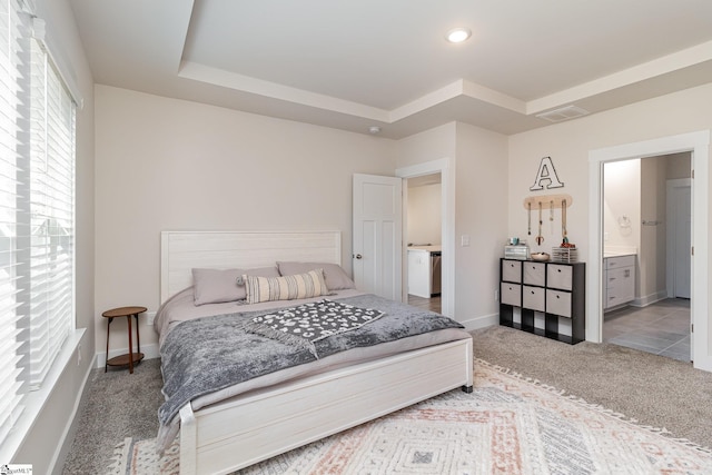 bedroom featuring carpet flooring, a raised ceiling, and ensuite bath