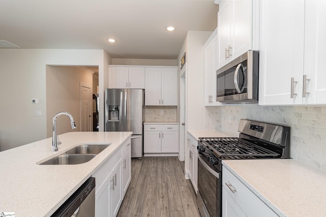 kitchen featuring light stone countertops, stainless steel appliances, sink, light hardwood / wood-style flooring, and white cabinetry