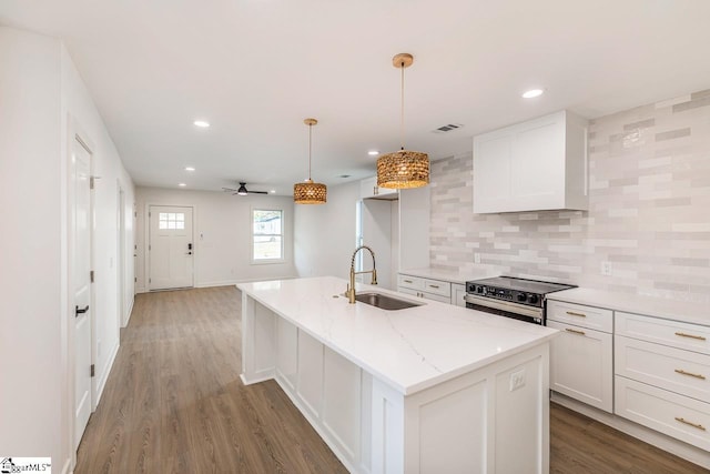 kitchen with dark wood-type flooring, sink, a center island with sink, white cabinets, and hanging light fixtures