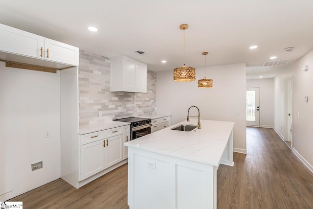 kitchen with pendant lighting, stainless steel range with electric stovetop, white cabinets, sink, and light stone counters