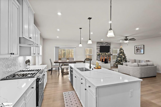 kitchen featuring a center island with sink, white cabinets, stainless steel appliances, and light hardwood / wood-style floors