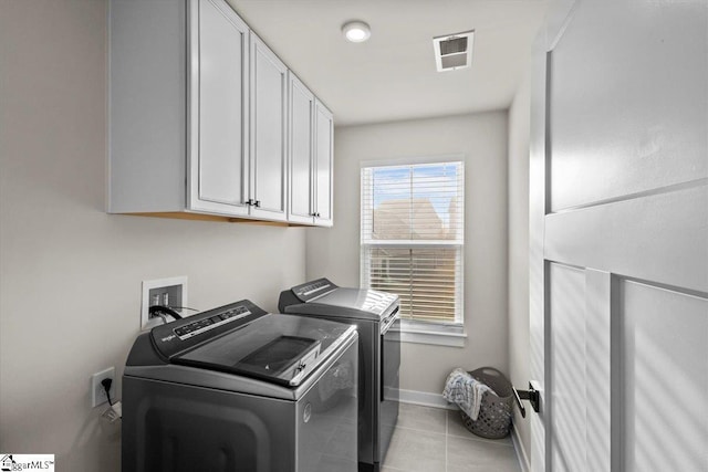 laundry room with cabinets, washer and dryer, and light tile patterned flooring