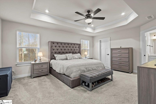 bedroom featuring ensuite bathroom, a raised ceiling, crown molding, ceiling fan, and light colored carpet