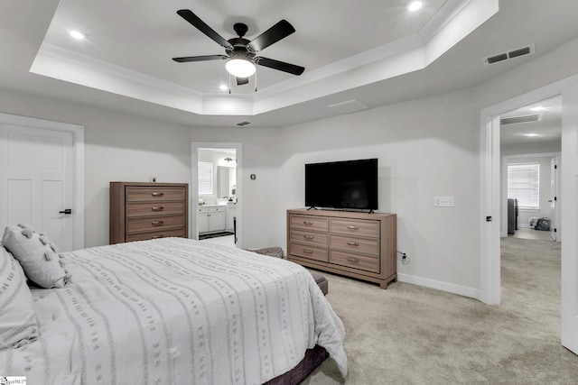 carpeted bedroom featuring ensuite bathroom, ceiling fan, ornamental molding, and a tray ceiling