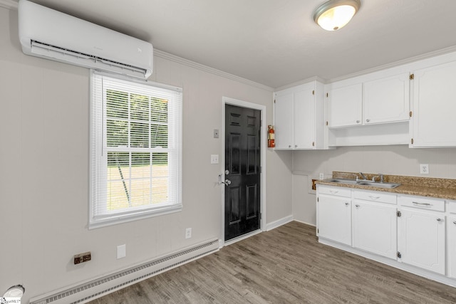 kitchen featuring white cabinets, light wood-type flooring, baseboard heating, and a wall mounted AC