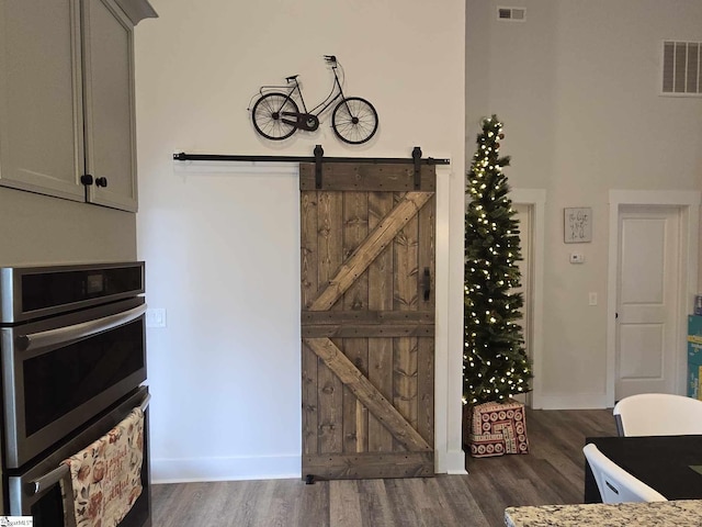 dining area featuring a barn door and dark wood-type flooring