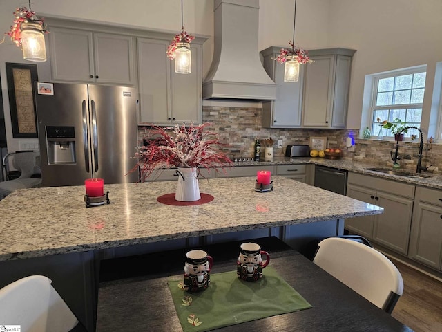 kitchen featuring decorative backsplash, custom exhaust hood, stainless steel appliances, sink, and pendant lighting