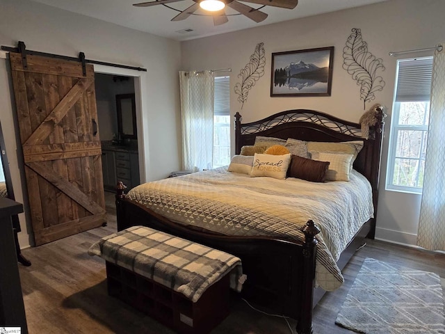 bedroom featuring ceiling fan, a barn door, and dark wood-type flooring